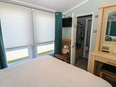 A bedroom with a bed, chair, and television at A and C Lodge-Plot 21 Armathwaite