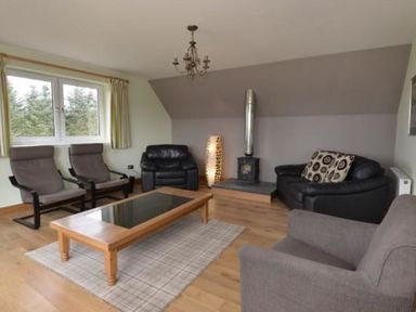 A living room with armchairs and a wood-burning stove at Glen View Lodge in Drumnadrochit Loch Ness