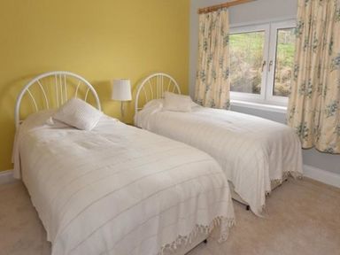 A bedroom with two single beds and a lamp between them at Glen View Lodge in Drumnadrochit Loch Ness