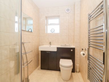 A bathroom with a toilet sink cabinet mirror towel rack and window at Riverview Apartment in Cemaes Bay