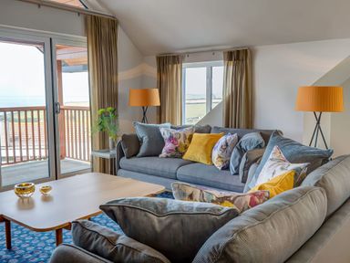 A living room with two sofas with colorful cushions a wooden coffee table and floor lamps at Villa 1 Mullion