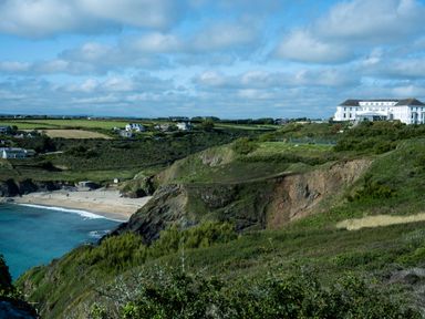 A coastal landscape with cliffs a sandy beach and buildings on a hillside at Villa 1 in Mullion