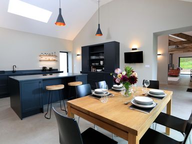 A kitchen with a dining table set with plates and glasses and a flower vase at The Barns @ Downton in Dittisham