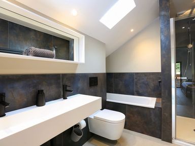 A bathroom with a bathtub toilet double sink and shower area at The Barns @ Downton in Dittisham
