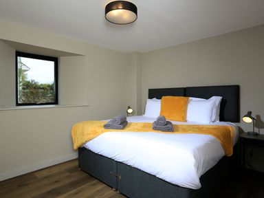 A bedroom with a bed with white linens yellow blanket and pillow beside a window at The Barns @ Downton in Dittisham