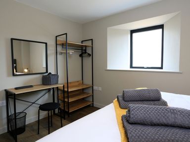 A bedroom corner with a desk stool mirror open closet and bed with towels near a window at The Barns @ Downton in Dittisham