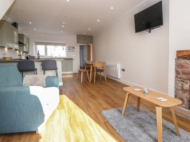 A living room with a blue armchair wooden coffee table and wall mounted TV at 2 South Street in Fletchertown near Aspatria