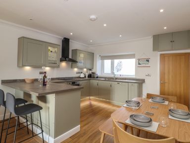 A kitchen with a dining table set for four and bar stools at 2 South Street in Fletchertown near Aspatria