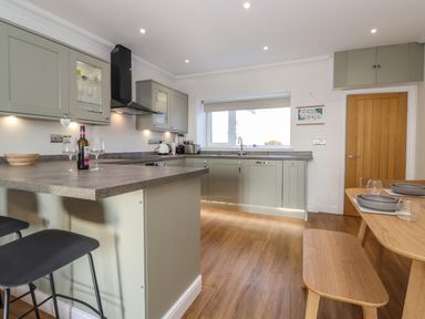 A kitchen with countertop bar stools and dining table with bench at 2 South Street in Fletchertown near Aspatria