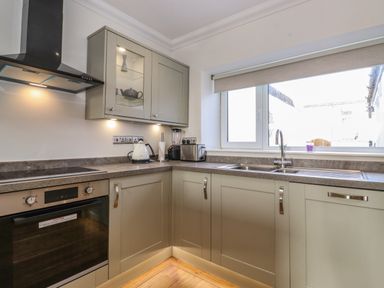 A kitchen with an oven, stovetop, kettle, blender, under cabinet lighting and a window at 2 South Street in Fletchertown near Aspatria
