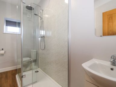 A bathroom with a shower enclosure toilet sink mirror and window at 2 South Street Fletchertown near Aspatria