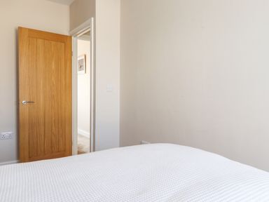 A bedroom with a wooden door partially open and a bed with a white textured cover at 2 South Street in Fletchertown near Aspatria