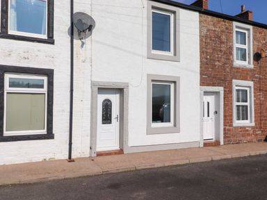 Exterior view of terraced houses with white and red brick facades and white doors at 2 South Street Fletchertown near Aspatria