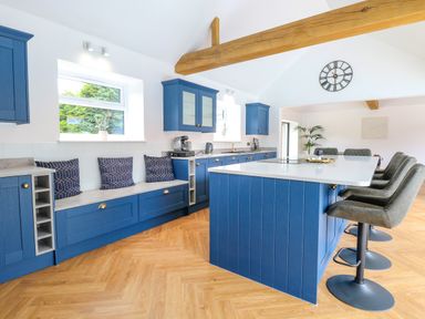 A kitchen with blue cabinets a white island and bar stools at County Farm Barn in South Walsham