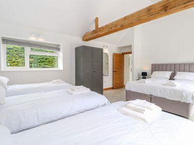A bedroom with three single beds and one double bed a wardrobe and window at County Farm Barn in South Walsham