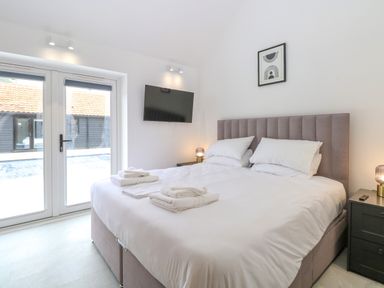 A bedroom with a double bed pillows and towels by glass doors at County Farm Barn in South Walsham