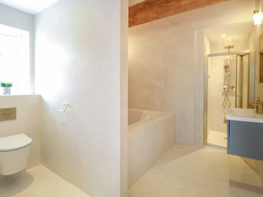A bathroom with a wall-mounted toilet bathtub shower and sink at County Farm Barn South Walsham