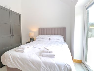 A bedroom with a bed white bedding towels on the bed a bedside lamp and a gray wardrobe at County Farm Barn in South Walsham
