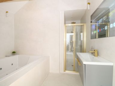 A bathroom with a bathtub a shower with glass doors and a sink with a mirror at County Farm Barn in South Walsham
