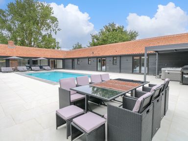 An outdoor pool area with seating and tables at County Farm Barn in South Walsham