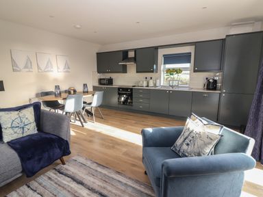 A kitchen and dining area with dark cabinets a dining table with four chairs and two armchairs at The Boathouse in Carrigaholt County Clare