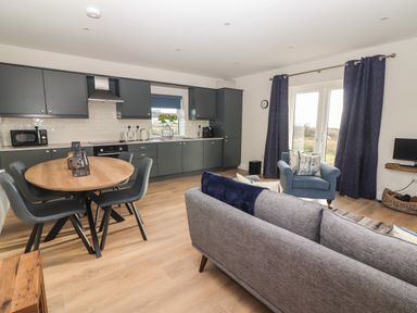 An open plan kitchen and living room with a dining table and chairs at The Boathouse in Carrigaholt County Clare