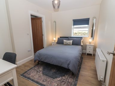 A bedroom with a bed a rug bedside tables and a window at The Boathouse in Carrigaholt County Clare
