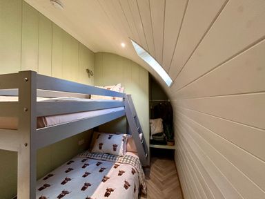 A bunk bed with a ladder and clothing rack at Willow in Llangurig near Llanidloes