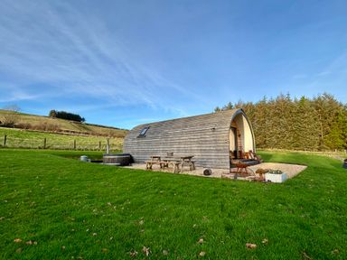 A wooden pod with patio furniture and a hot tub at Willow in Llangurig near Llanidloes