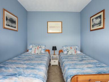 A bedroom with two single beds and a nightstand with a lamp at Waters Edge Ymyl Y Dwr in Y Felinheli