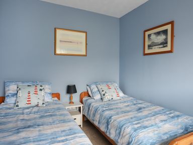 A bedroom with two single beds and a bedside table with a lamp at Waters Edge Ymyl Y Dwr in Y Felinheli