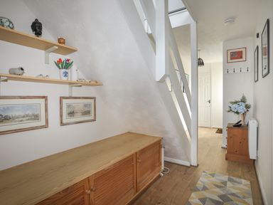 A hallway with wooden furniture shelves wall art and a carpet at Waters Edge Ymyl Y Dwr in Y Felinheli