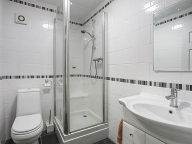 A bathroom with a toilet shower enclosure and sink at Waters Edge Ymyl Y Dwr in Y Felinheli