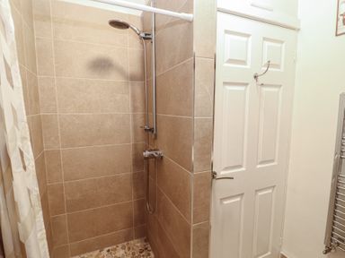 A shower area with a shower head and wall tiles at River Cottage in Eamont Bridge