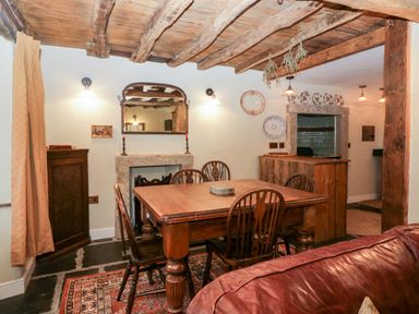 A dining area with wooden table and chairs a mirror above a fireplace and decorative plates on the wall in Eden Vale Broughton-In-Furness