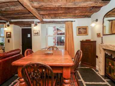 A dining room with a wooden table and chairs with a curtain on the window at Eden Vale in Broughton-In-Furness