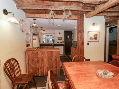 A kitchen and dining area with wooden furniture and hanging dried herbs at Eden Vale in Broughton-In-Furness