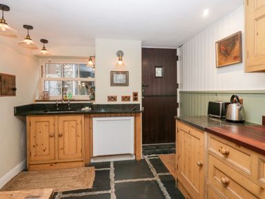 A kitchen with wooden cabinets a black countertop a dark wooden door a toaster and kettle on the counter at Eden Vale in Broughton-In-Furness
