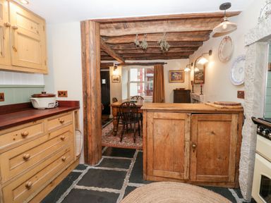 A kitchen with wooden cabinets and an island opening to a dining area with a wooden table and chairs at Eden Vale in Broughton-In-Furness