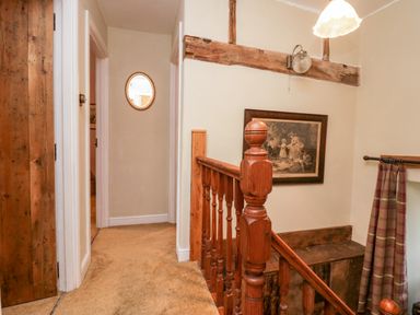 A hallway with carpeted floor wooden banister framed painting and mirror at Eden Vale in Broughton-In-Furness