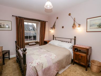 A bedroom with a metal bed frame bedside tables wall lights and framed pictures at Eden Vale in Broughton-In-Furness