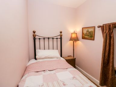 A small bedroom with a single bed a bedside table with a lamp a painting on the wall and patterned curtains at Eden Vale in Broughton-In-Furness