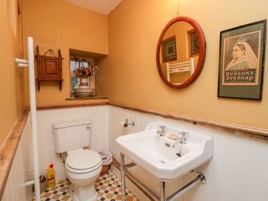 A bathroom with a toilet sink round mirror framed picture and a small window at Eden Vale in Broughton-In-Furness