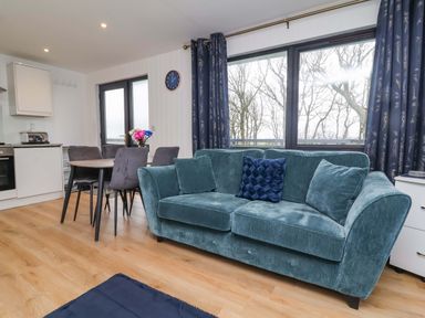 A living room with a sofa and dining area at Cassia in Kilkhampton