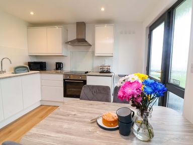 A kitchen with a dining table and flowers at Cassia in Kilkhampton