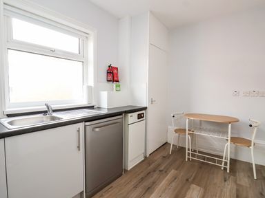 A kitchen with a sink dishwasher small dining table and two chairs at 46 The Promenade in Withernsea