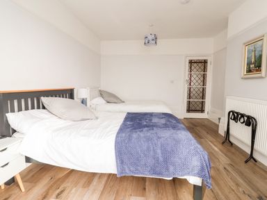A bedroom with two single beds a blue blanket wooden floor and a painting on the wall at 46 The Promenade in Withernsea