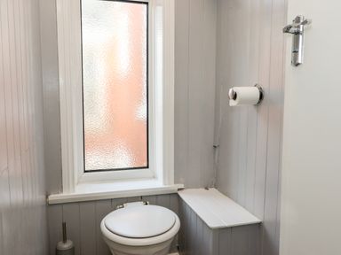 A small bathroom with a toilet, frosted window, toilet brush holder, and a toilet paper holder on the wall at 46 The Promenade in Withernsea