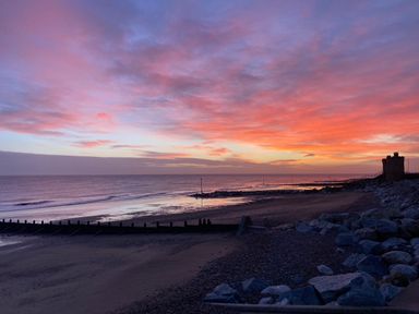 A beach at sunset with rocks and a small building near the shore at 46 The Promenade in Withernsea