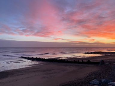 A beach with a wooden groyne extending into the sea at sunset at 46 The Promenade in Withernsea